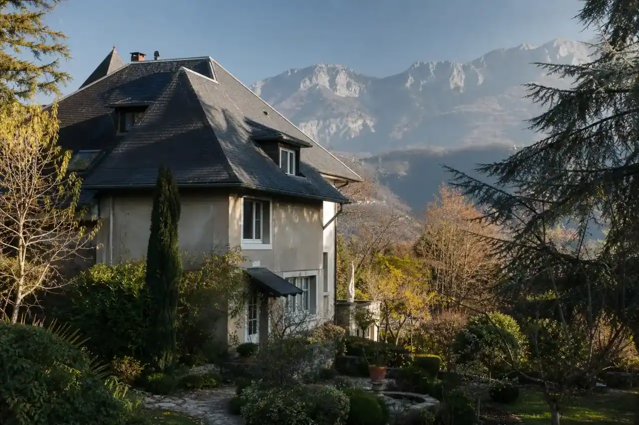 maison traditionnelle de caractère avec toit en ardoise, jardin arboré, cadre de sud-agglomération vallonné, lumière de matin, aucune personne visible