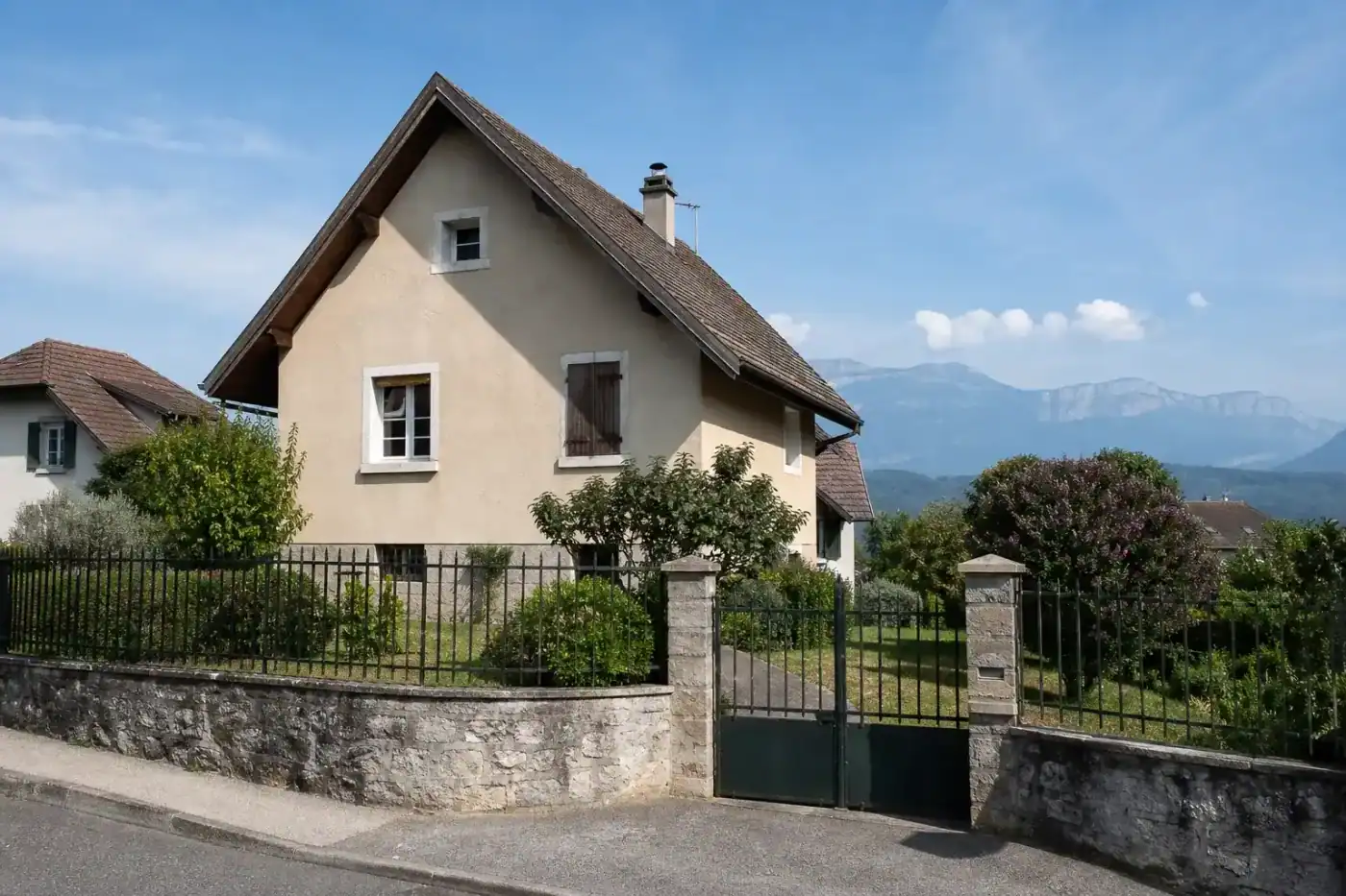 maison traditionnelle avec toit à forte pente typique du Voironnais, façade enduite ton pierre, jardin clos, journée ensoleillée, aucune personne visible