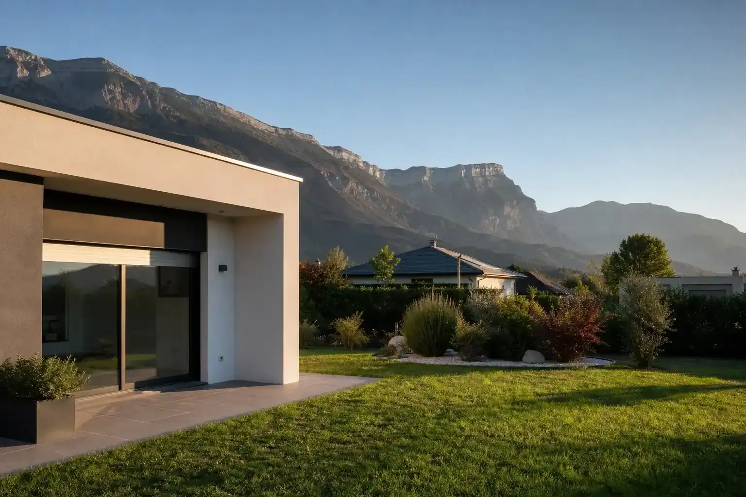 maison individuelle contemporaine achevée dans l'agglomération grenobloise, toiture nette, jardin engazonné, massifs du Vercors ou de la Chartreuse en arrière-plan, fin d'après-midi, aucune personne visible