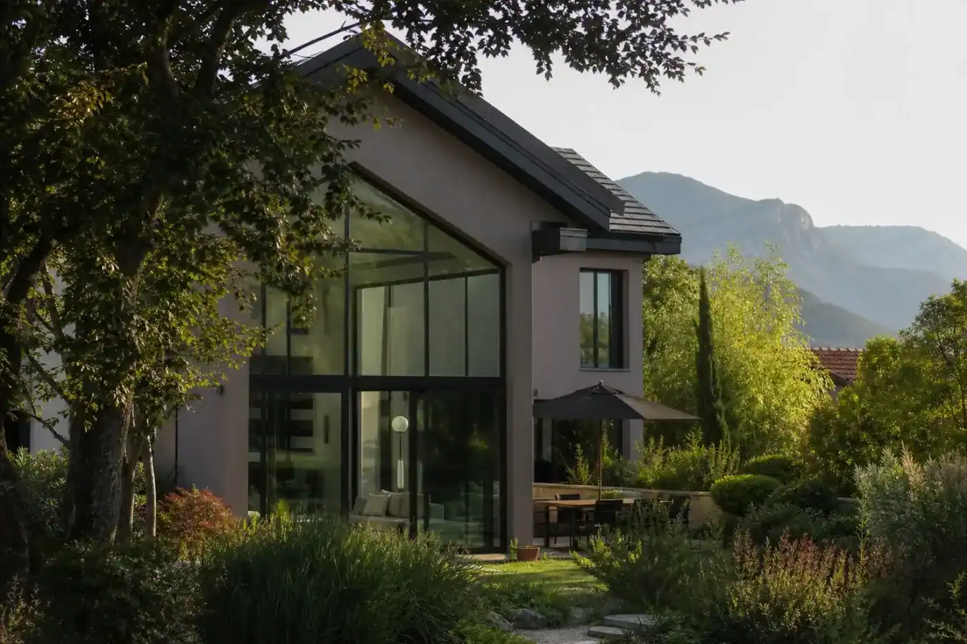 maison contemporaine avec grande verrière, jardin paysager arboré, proche d'un parc d'activités, lumière de fin d'après-midi, aucune personne visible